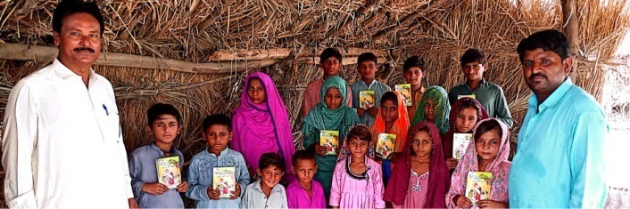 Group of Pakistani children with two adults all huddled in an open tent