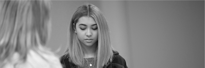 Black and white of a sad young woman speaking with another woman