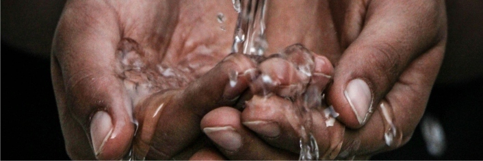 Hands cupped together gathering water pouring over them