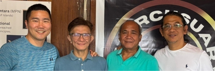 Four men standing side by side smiling at camera