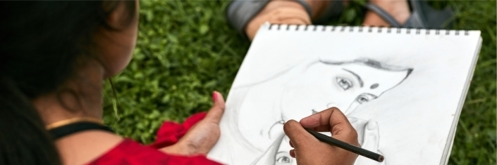 A young woman drawing a pencil sketch of a mother and her infant