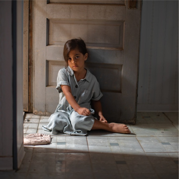 Young asian girl sitting on the floor looking saddly at camera