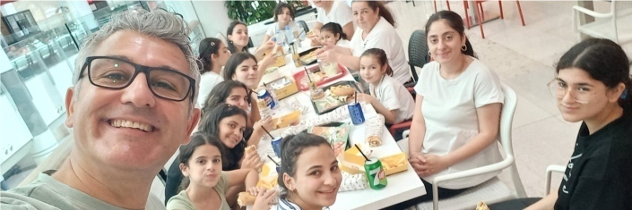 Man taking selfee with a group of young girls in the background