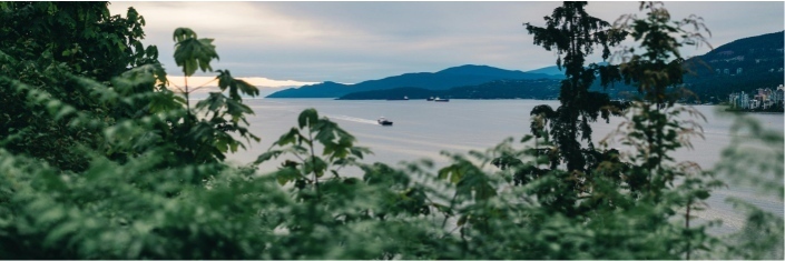 Calm lake with grey skies and mountains in background small boat on the water