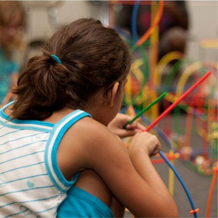 Girl with back to camera playing with toys.