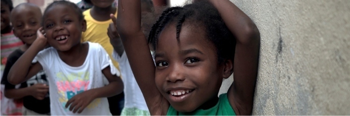 Three little Haitian girls smiling at the camera