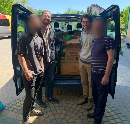 Fellowship missionaries and Ukrainian refugees standing with a van full of supplies