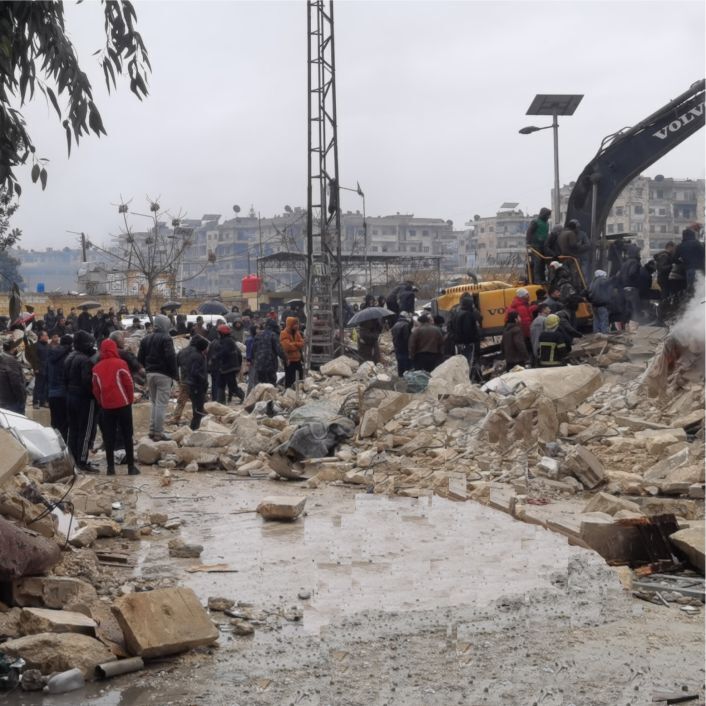 The aftermath of earthquake machinery and people rescuing people from rubble.