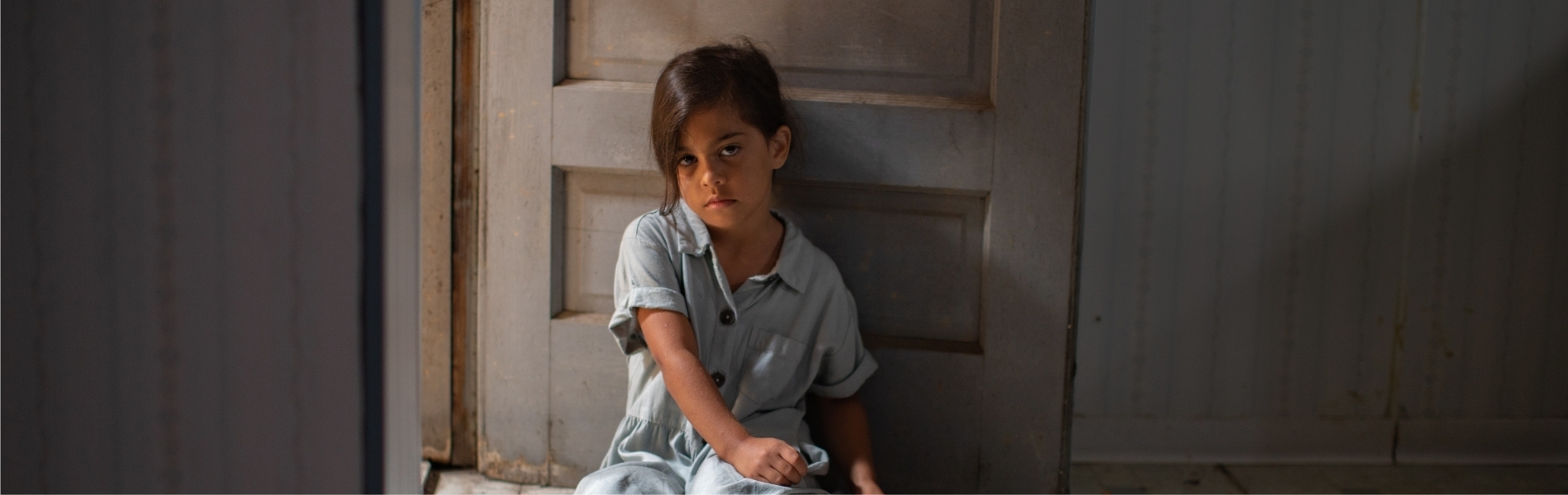Young child sitting on the floor looking very sad